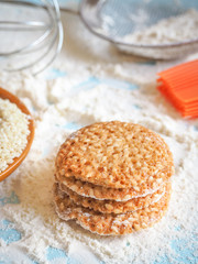 top view of product set for cooking cookies, kitchenware and several round cookies with sesame on a blue wooden table