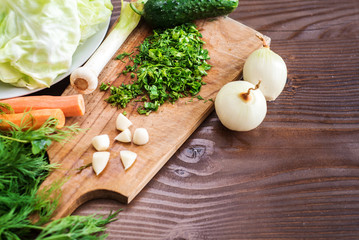 Chopped onion and herbs with other vegetables on woden board. Preparation for cooking