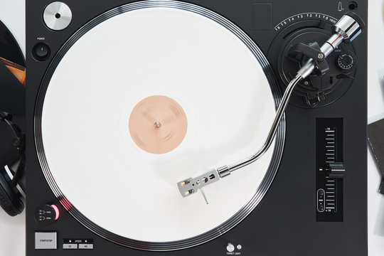 Turntable vinyl record player on the background white wooden boards. Sound technology for DJ to mix & play music. Needle on a vinyl record. White vinyl record                            