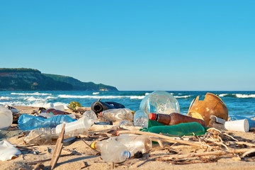 Spilled garbage on the beach of the big city. Empty used dirty plastic bottles. Dirty sea sandy shore the Black Sea. Environmental pollution. Ecological problem. Bokeh moving waves in the background  