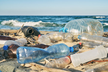 Spilled garbage on the beach of the big city. Empty used dirty plastic bottles. Dirty sea sandy...