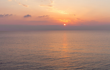 Obraz premium Sky turning orange. The sun setting down in the sea. Clouds and waves meeting up in the ocean. Unwinding activity in the beach. Sunset watching moment.