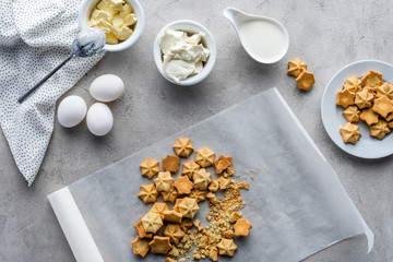 flat lay with cookies, raw chicken eggs, butter and sour cream for making pie arranged on grey tabletop