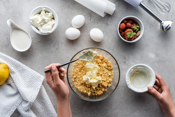 cropped shot of woman making dough for homemade pie with arranged ingredients around on grey tabletop