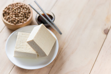 Food product including tofu, and soy sauce made from soybean on wooden background, natural source of protein for vegetarian