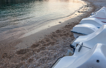 Jet ski lining up. The water sports vehicle park above the sand. Tides getting low. Pebbles and crushed corals scattering around. Beach activities and fun ride in the sea.