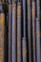 Obraz premium Oil Drill pipe. Rusty drill pipes were drilled in the well section. Downhole drilling rig. Laying the pipe on the deck. View of the shell of drill pipes laid in courtyard of the oil and gas warehouse.
