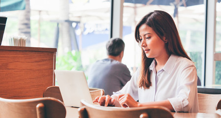 Asian Woman drinking coffee at morning breakfast during working at cafe' banner. Happy Asian girl...