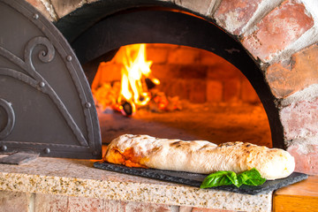 Rustic home-made stuffed pizza roll (Italian: rotolo di pizza farcito) baked in a wood fired brick...