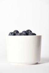 close up view of bowl with blueberries on grey background