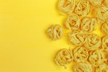 Close up of a raw dry italian pasta fettuccine on bright yellow background. Shooting with bold color.