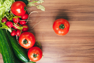 Fresh vegetables tomatoes, cucumbers, and spices on wooden background. Copy space