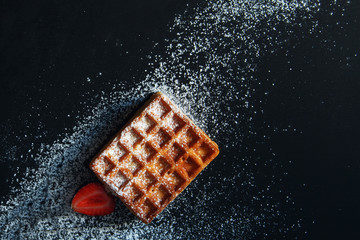 Belgian waffles with strawberry and powdered sugar.