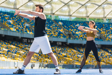 young beautiful couple warming up before training on running track at sports stadium