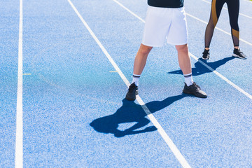 Fototapeta na wymiar cropped shot of man and woman in modern sportswear standing on running track
