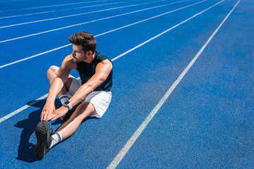 handsome young man stretching on running track