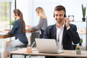 Male receptionist with headset at desk in office