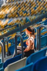 Fototapeta premium high angle view of beautiful young woman relaxing on stairs at sports stadium