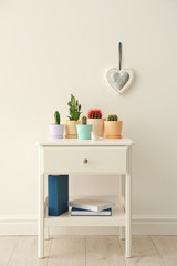Fototapeta premium Beautiful cacti on table near light wall