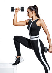Fitness girl performs exercising with dumbbells for hands. Photo of sporty girl in black...