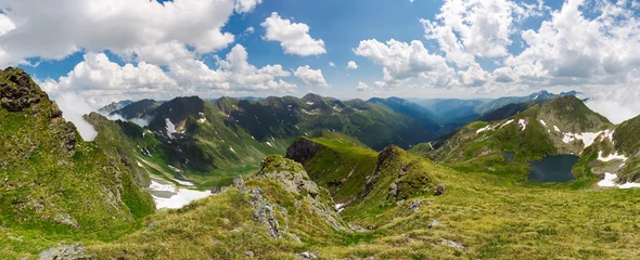 panorama of Fagaras mountain ridge in summer. beautiful view in to the valley of beautiful landscape with gorgeous cloudscape. rocky cliffs above the grassy slopes with some snow.  © Pellinni