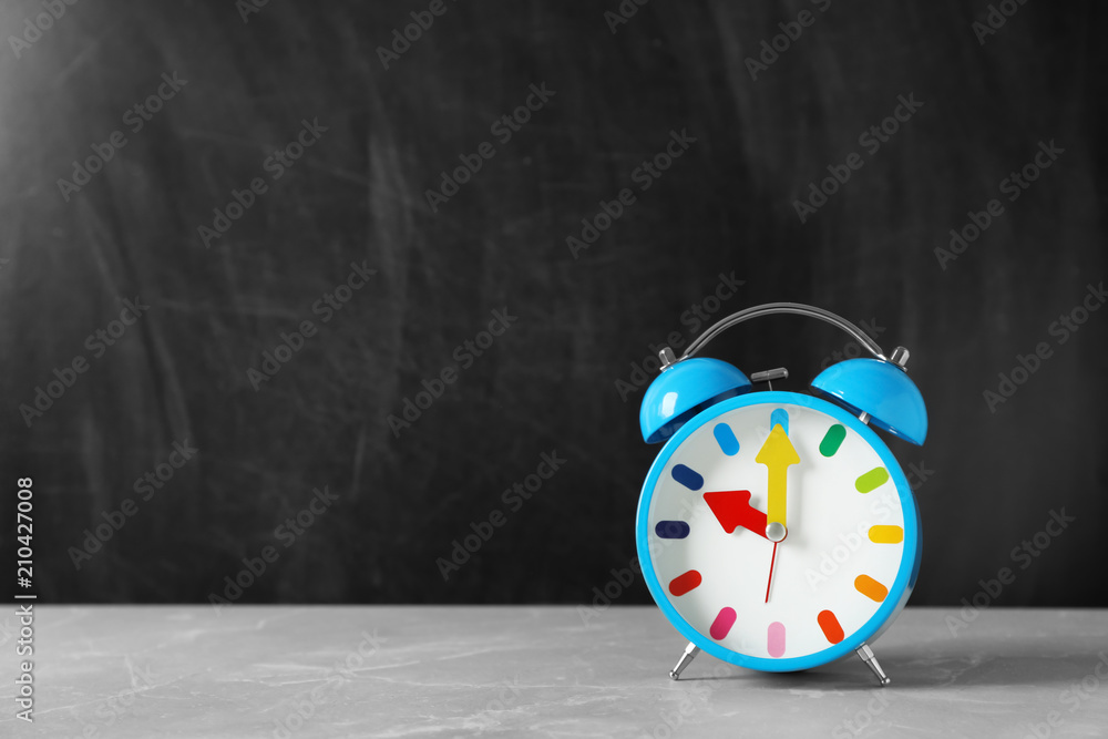 Poster Alarm clock on table against color background. Time concept