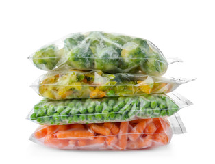 Plastic bags with frozen vegetables on white background