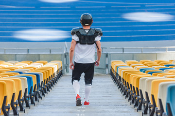rear view of sportive american football player on stairs at sports stadium