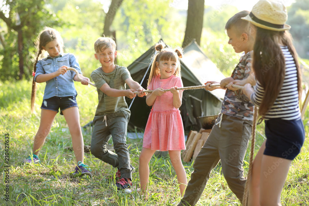 Wall mural little children pulling rope outdoors. summer camp