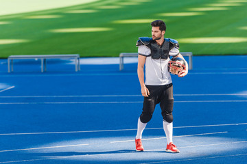 Obraz premium attractive young american football player standing alone at sports stadium