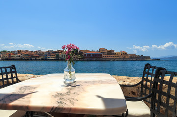 Fototapeta premium Cafe with marble tables on the sea coast in Chania, Crete island, Greece. Selective focus