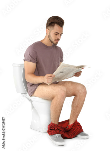 View Of Man Reading Newspaper While Sitting On Toilet Bowl 