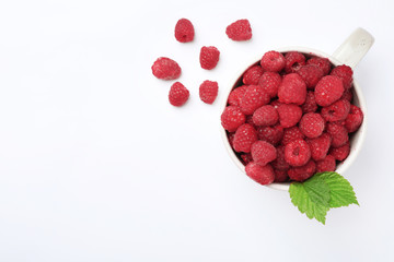 Mug with ripe raspberries on white background, top view