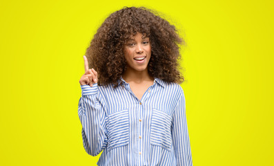 African american woman wearing a stripes shirt surprised with an idea or question pointing finger...