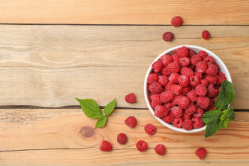 Bowl with ripe aromatic raspberries on wooden table, top view © New Africa