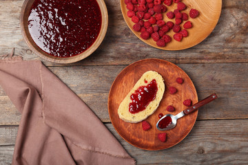 Beautiful composition with delicious raspberry jam on wooden table, top view