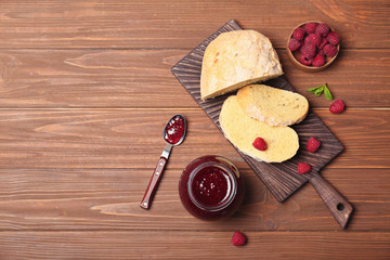 Beautiful composition with delicious raspberry jam on wooden table, top view