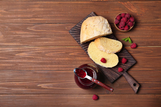 Beautiful composition with delicious raspberry jam on wooden table, top view