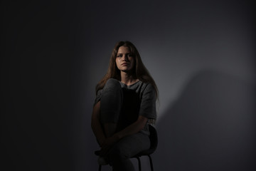 Depressed young woman on gray background