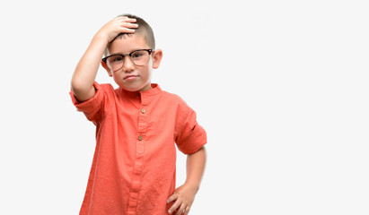 Fototapeta premium Dark haired little child wearing glasses stressed with hand on head, shocked with shame and surprise face, angry and frustrated. Fear and upset for mistake.