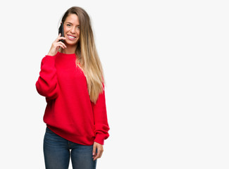 Fototapeta premium Beautiful young woman using smartphone with a happy face standing and smiling with a confident smile showing teeth