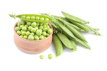 Fresh, green peas in a wooden bowl next to peas in a stitch on a white background. isolated