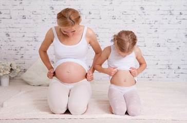 Pregnant mom and little girl comparing bellies