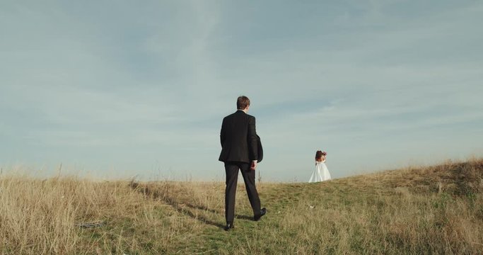 Groom walking to with his bride in the middle of landscape