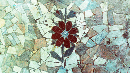 A mosaic In the form of a flower made of stone on the floor in an old industrial building of the Soviet period (seventies).