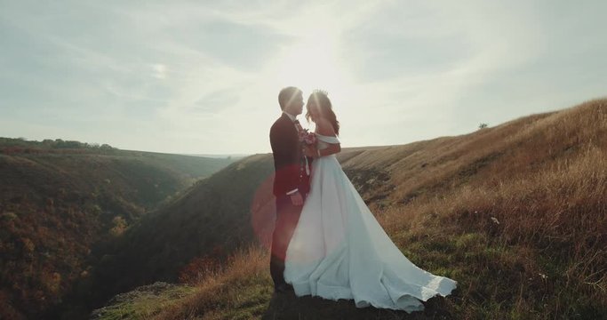 Beautiful groom and bride stand together in the peak of mountain.