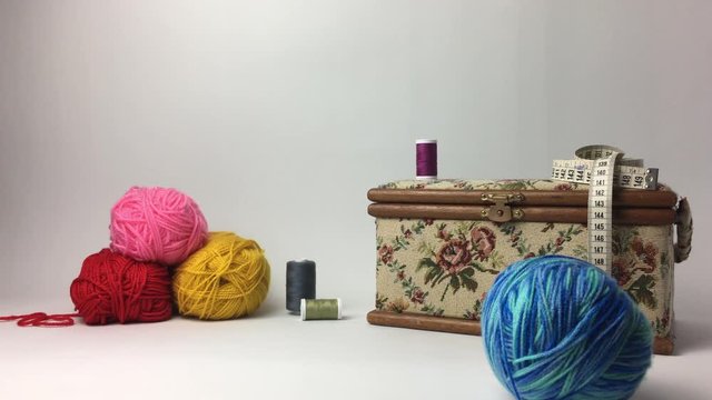 Ovillo de lana rodando junto a caja de costura.2