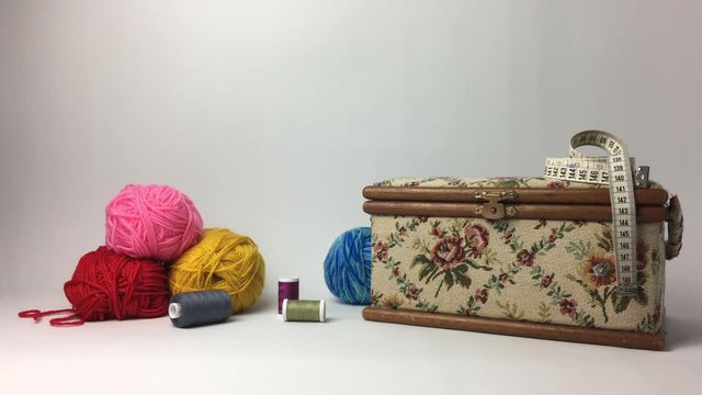 Caja de costura con ovillo de hilo rodando por la derecha.