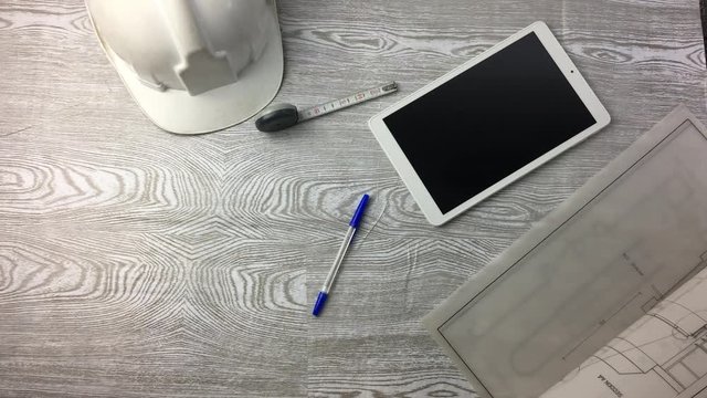 Mesa de trabajo con planos y tablet.