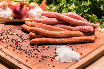 raw sausages with chilli and herbs on a wooden board with spices